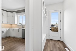 Open concept kitchen featuring white cabinetry, under-cabinet lighting, a corner sink with a black faucet, and a stainless steel dishwasher - 
