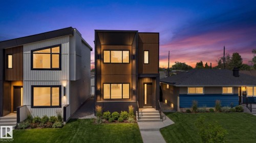 Modern two-story facade featuring dark-framed windows, a flat roofline, vertical panel siding, exterior wall sconces, and a neatly manicured lawn - 5308 103A Avenue, Edmonton, AB - Outdoor With Facade