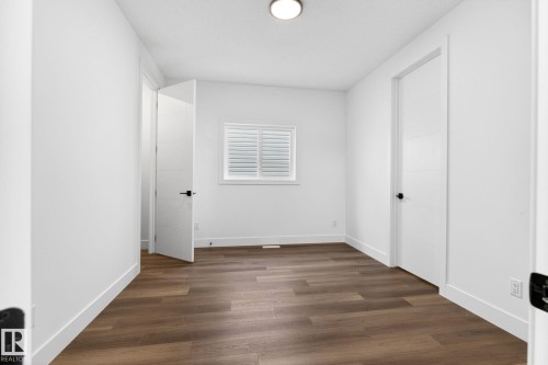 Room featuring wood-finish flooring, white baseboards, and bright white walls - 5308 103A Avenue, Edmonton, AB - Indoor Photo Showing Other Room