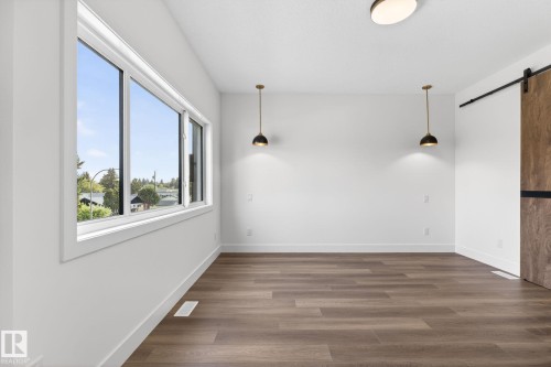 Spacious room featuring wood-finish flooring, white baseboards, and a large multi-pane window - 5308 103A Avenue, Edmonton, AB - Indoor Photo Showing Other Room