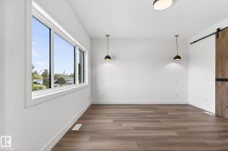 Spacious room featuring wood-finish flooring, white baseboards, and a large multi-pane window - 