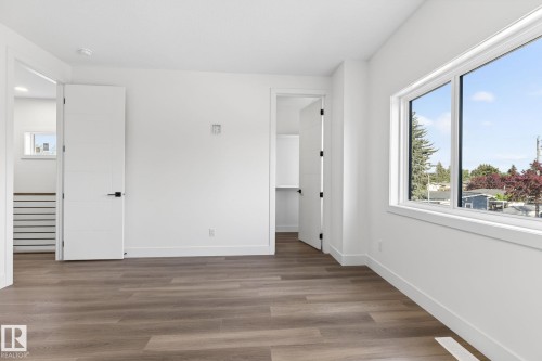 Spacious room featuring wood-finish flooring, white walls, and a large window - 5308 103A Avenue, Edmonton, AB - Indoor Photo Showing Other Room