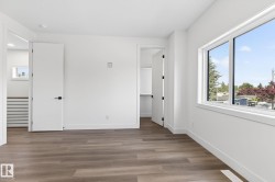 Spacious room featuring wood-finish flooring, white walls, and a large window - 