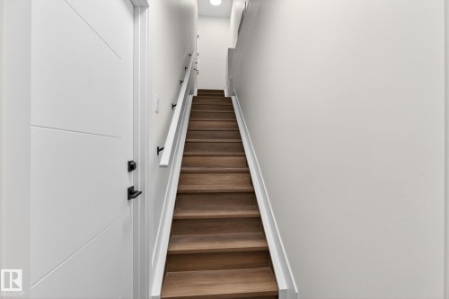 Hardwood staircase with white risers and handrail, featuring black rail supports - 5308 103A Avenue, Edmonton, AB - Indoor Photo Showing Other Room