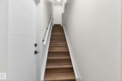 Hardwood staircase with white risers and handrail, featuring black rail supports - 