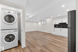 Open concept living space featuring wood-finish flooring, recessed lighting, and a kitchen area with white cabinetry, a dark backsplash, and a built-in refrigerator - 