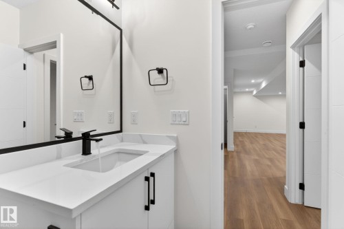 Contemporary vanity featuring a white countertop with integrated sink, matte black faucet, and coordinating hardware - 5308 103A Avenue, Edmonton, AB - Indoor Photo Showing Bathroom