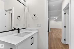 Contemporary vanity featuring a white countertop with integrated sink, matte black faucet, and coordinating hardware - 