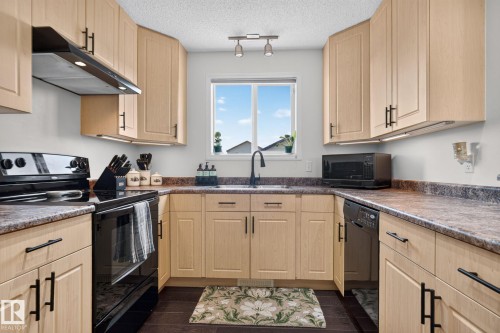 U-shaped kitchen with light wood-finish cabinetry, dark countertops, and a window above the sink - 191 Brookview Place, Stony Plain, AB - Indoor Photo Showing Kitchen