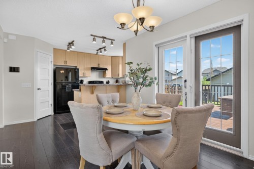 Dining area featuring dark wood-finish flooring, a contemporary chandelier, and French doors leading to an exterior deck - 191 Brookview Place, Stony Plain, AB - Indoor Photo Showing Dining Room