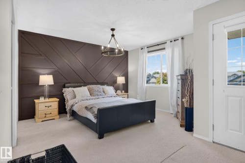 Feature wall with geometric paneling and a modern chandelier - 191 Brookview Place, Stony Plain, AB - Indoor Photo Showing Bedroom