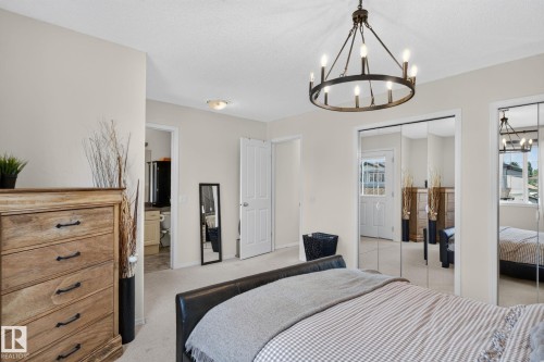 Spacious room featuring neutral wall tones, a wagon wheel chandelier, and mirrored closet doors - 191 Brookview Place, Stony Plain, AB - Indoor Photo Showing Bedroom