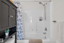 Integrated bathtub and shower combination featuring a white surround and chrome fixtures - 