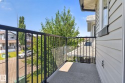 Exterior balcony featuring a concrete floor, black metal railings, and a partial clear panel - 