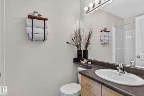 Bathroom vanity with a curved countertop, integrated sink, and wood-finish cabinetry - 191 Brookview Place, Stony Plain, AB - Indoor Photo Showing Bathroom