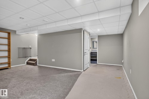 Versatile finished basement space featuring light gray walls, a partial carpeted floor, and a drop ceiling with recessed lighting - 191 Brookview Place, Stony Plain, AB - Indoor