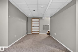 Carpeted lower-level room with suspended acoustic ceiling tiles and recessed lighting - 