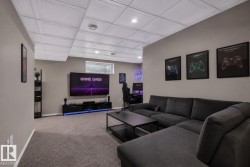 Spacious recreational room featuring gray carpeting, light gray walls, and a white grid ceiling - 