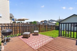 Expansive wood-finish deck featuring dark-stained railings and a direct egress to the green lawn - 