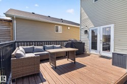 Spacious wood-finish deck with black metal railings, offering direct access to the interior via double French doors - 