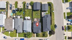 Property featuring a shingled roof, a paved driveway, and a front yard with manicured landscaping - 