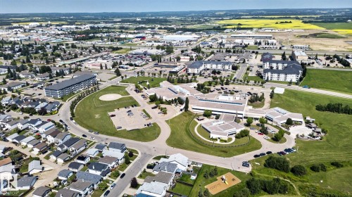 Aerial perspective showcasing a mixed-use community with residential homes, multi-story buildings, and commercial structures - 191 Brookview Place, Stony Plain, AB - Outdoor With View