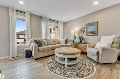 Spacious living area featuring wood-finish flooring, recessed lighting, and multiple large windows - #25 1530 Tamarack Bv Nw, Edmonton, AB - Indoor Photo Showing Living Room