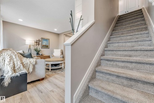 Carpeted staircase with white trim, featuring a partial shiplap wall accent - #25 1530 Tamarack Bv Nw, Edmonton, AB - Indoor Photo Showing Other Room