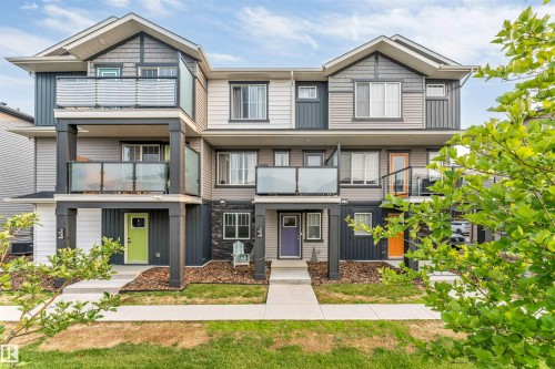 Contemporary multi-level townhome featuring a mixed material facade with horizontal siding, vertical accents, and stone details - #25 1530 Tamarack Bv Nw, Edmonton, AB - Outdoor With Facade