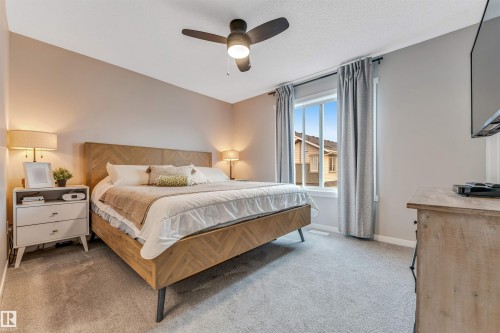 Bedroom featuring light gray carpeting, neutral wall tones, a ceiling fan with integrated lighting, and a double-pane window - #25 1530 Tamarack Bv Nw, Edmonton, AB - Indoor Photo Showing Bedroom