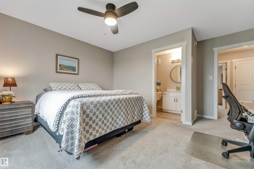 Carpeted bedroom featuring a ceiling fan with integrated lighting, two doorways, and neutral wall tones - #25 1530 Tamarack Bv Nw, Edmonton, AB - Indoor Photo Showing Bedroom