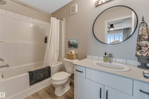 Bathroom featuring a white tub with subway tile surround, a toilet, and a vanity with an integrated sink - #25 1530 Tamarack Bv Nw, Edmonton, AB - Indoor Photo Showing Bathroom