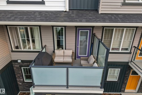 Private balcony featuring frosted glass railings and a distinct purple entry door - #25 1530 Tamarack Bv Nw, Edmonton, AB - Outdoor With Deck Patio Veranda With Exterior