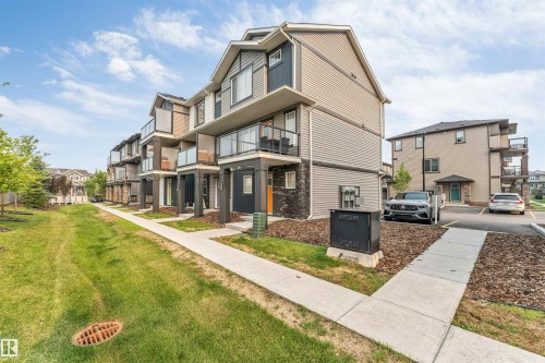 Multi-level residential building featuring horizontal siding, stone veneer accents, and multiple balconies with glass railings - #25 1530 Tamarack Bv Nw, Edmonton, AB - Outdoor