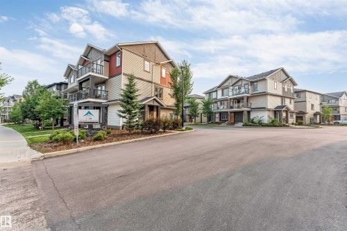 Contemporary multi-story residential buildings featuring varied siding materials, private balconies with glass railings, and mature landscaping - #25 1530 Tamarack Bv Nw, Edmonton, AB - Outdoor With Facade