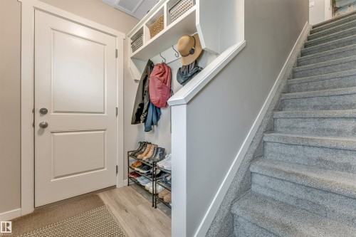 Entryway mudroom area featuring built-in shelving, coat hooks, and durable wood-finish flooring - #25 1530 Tamarack Bv Nw, Edmonton, AB - Indoor Photo Showing Other Room