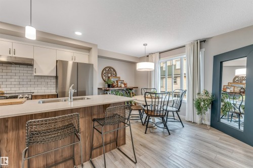 Modern kitchen and dining area featuring light wood-finish flooring - #25 1530 Tamarack Bv Nw, Edmonton, AB - Indoor