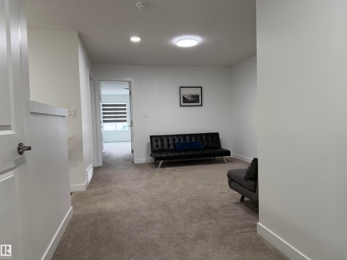 Carpeted interior space featuring recessed lighting, a contemporary ceiling light fixture, white trim, and a paneled door - 3631 213 Street Nw, Edmonton, AB - Indoor