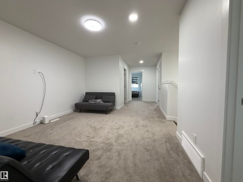 Carpeted open-concept bonus room featuring recessed and flush-mount lighting, white baseboards, and a hallway extension with additional recessed lighting - 3631 213 Street Nw, Edmonton, AB - Indoor Photo Showing Other Room