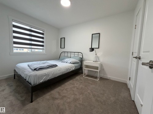 Light-filled room featuring a single window with horizontal blinds, neutral wall paint, and gray carpet flooring - 3631 213 Street Nw, Edmonton, AB - Indoor Photo Showing Bedroom