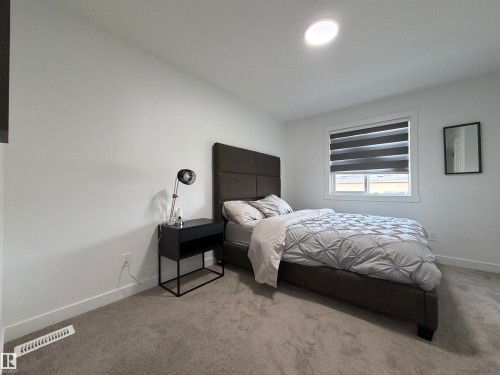 Carpeted bedroom featuring white walls, a recessed ceiling light, and a window with zebra blinds - 3631 213 Street Nw, Edmonton, AB - Indoor Photo Showing Bedroom