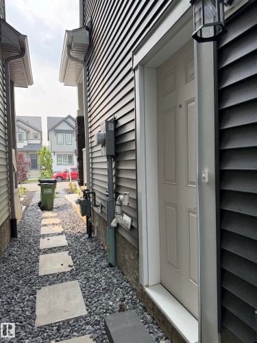 Exterior entry featuring dark horizontal siding and a complementary stone-clad foundation - 3631 213 Street Nw, Edmonton, AB - Outdoor With Exterior