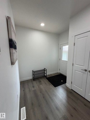 Entryway featuring wood-finish flooring, recessed lighting, white trim, and white interior doors with contemporary hardware - 3631 213 Street Nw, Edmonton, AB - Indoor Photo Showing Other Room