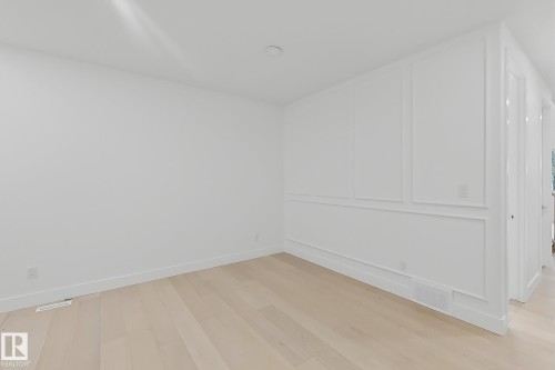 Crisp white walls with decorative molding, light wood-finish flooring, and recessed ceiling lighting - 8423 Mayday Link Link Sw, Edmonton, AB - Indoor Photo Showing Other Room