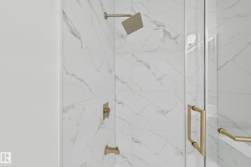 Shower enclosure featuring white marble-look tile, brushed gold fixtures, a rain showerhead, a square shower handle, and a clear glass door with a brushed gold pull handle - 8423 Mayday Link Link Sw, Edmonton, AB - Indoor Photo Showing Bathroom