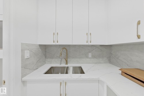 White cabinetry with gold-finish hardware, a dual-basin stainless steel sink, and a high-arc gold-finish faucet - 8423 Mayday Link Link Sw, Edmonton, AB - Indoor Photo Showing Kitchen