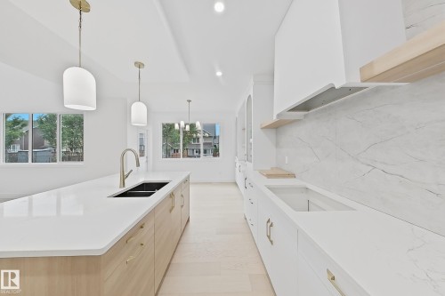 Bright kitchen featuring a substantial island with a built-in sink and contemporary faucet - 8423 Mayday Link Link Sw, Edmonton, AB - Indoor Photo Showing Kitchen With Double Sink