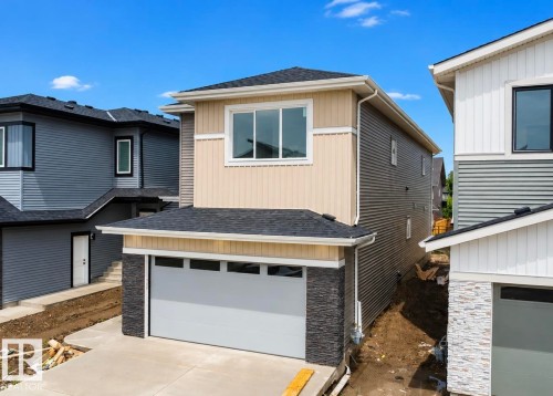 Two-story home with a light beige upper facade and dark gray siding on the lower level - 8423 Mayday Link Link Sw, Edmonton, AB - Outdoor With Exterior