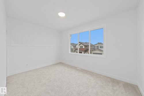 Carpeted room featuring a large window, recessed lighting, white walls, white baseboards, and wainscoting - 8423 Mayday Link Link Sw, Edmonton, AB - Indoor Photo Showing Other Room