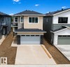 Contemporary two-story residence featuring a dual-tone facade, attached two-car garage with stone accents, and a paved driveway - 8423 Mayday Link Link Sw, Edmonton, AB  - Outdoor With Facade 